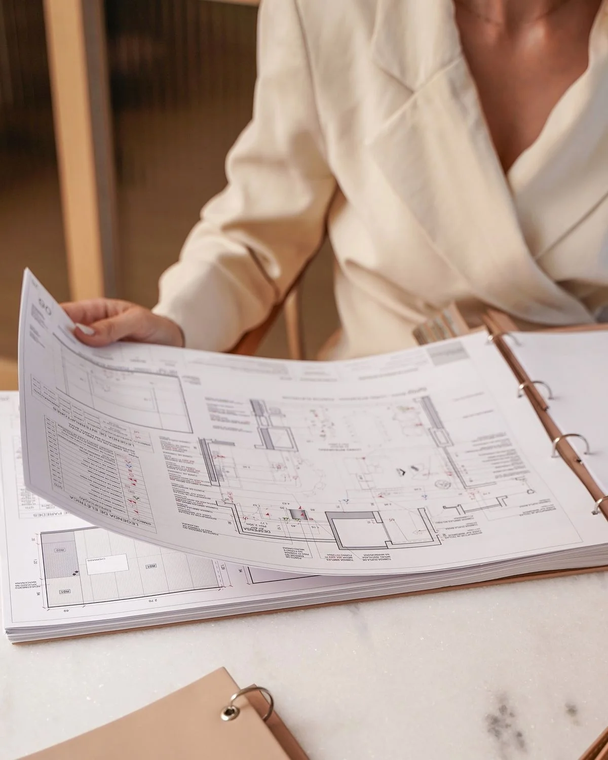 Architect reviewing a printed drawing set in a binder